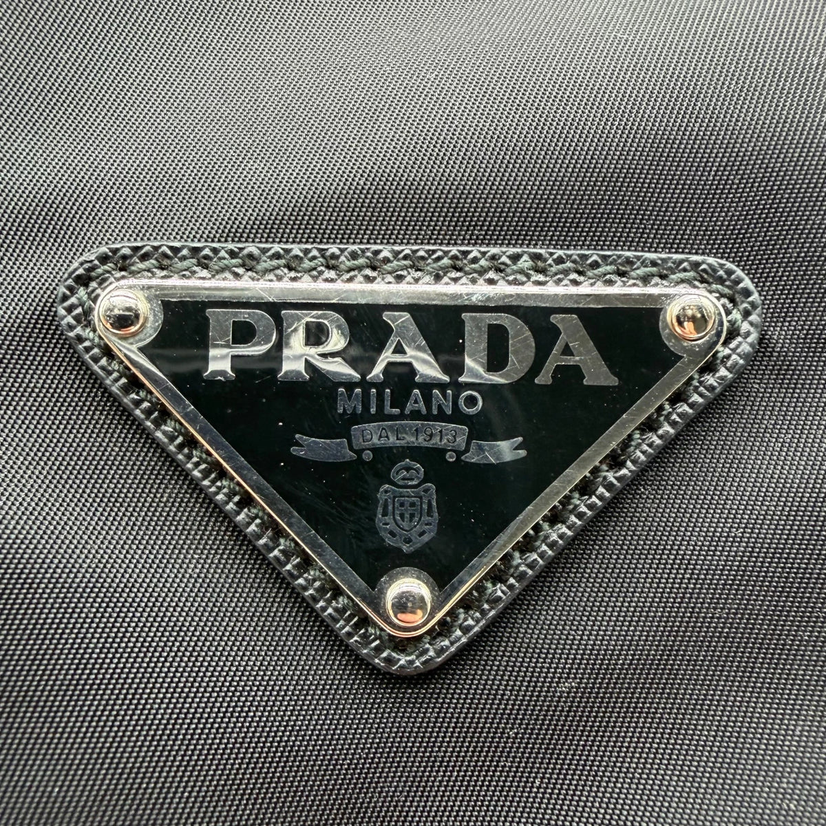 Prada Messengertasche AW18 Rockstar mit Nieten und seitlichen Taschen aus Nylon & Leder schwarz – Logo im Detail
